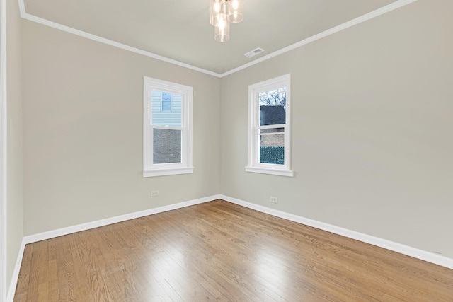 unfurnished room featuring baseboards, ornamental molding, wood finished floors, and visible vents