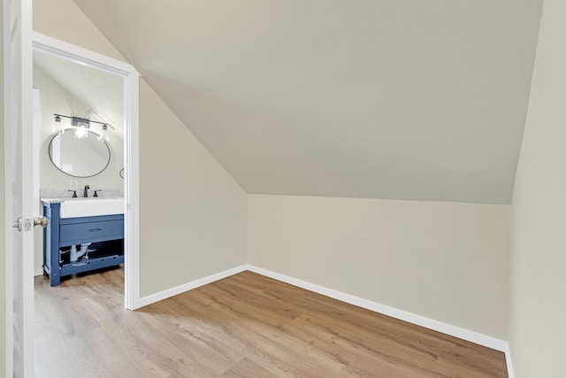 additional living space featuring baseboards, vaulted ceiling, and light wood-style flooring