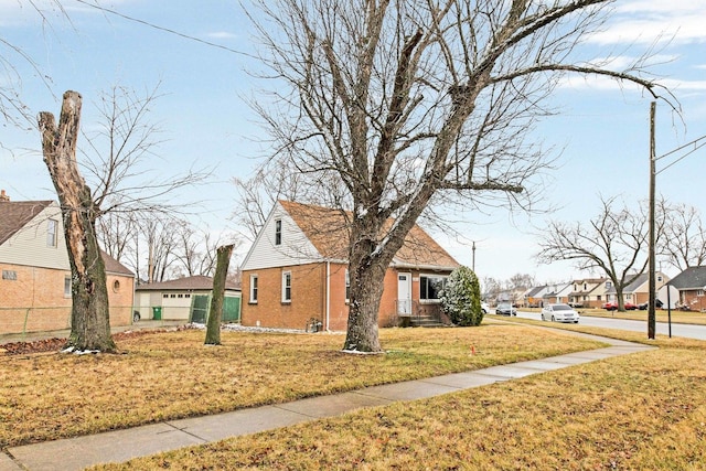 view of side of home with a residential view, fence, a yard, and brick siding