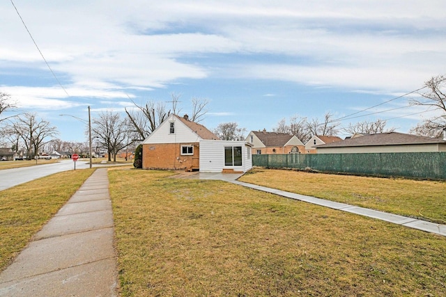 exterior space featuring brick siding, fence, and a front yard