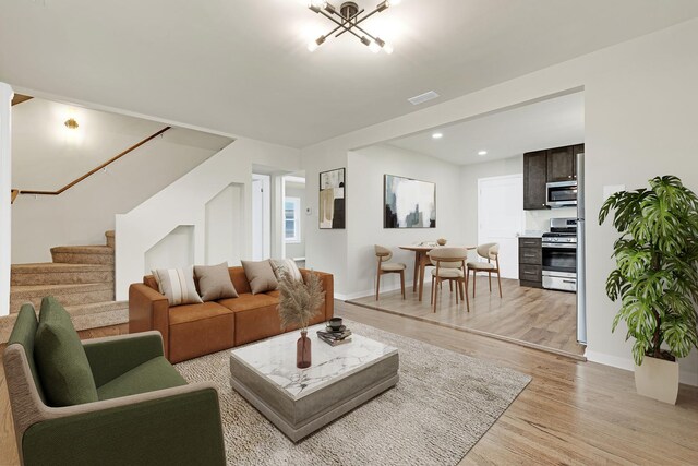 living room with visible vents, light wood-type flooring, stairs, baseboards, and recessed lighting
