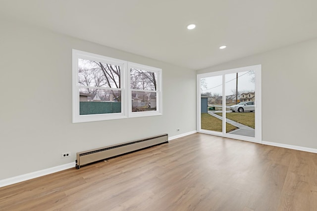 spare room with baseboards, a baseboard radiator, recessed lighting, and wood finished floors