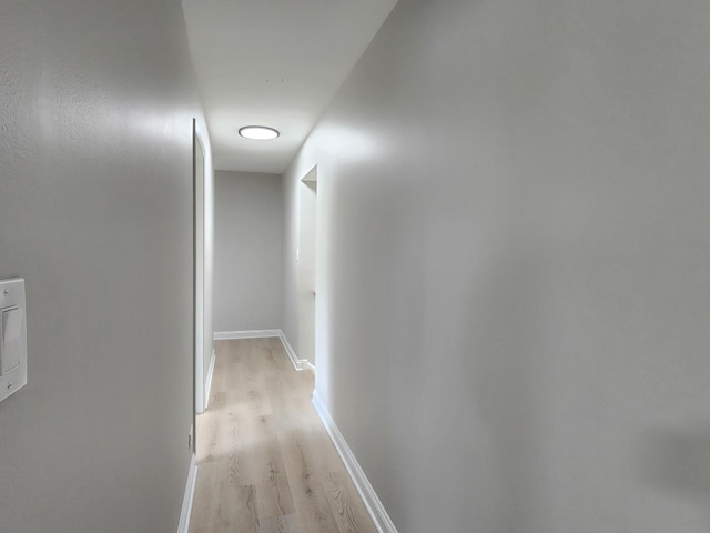 corridor featuring baseboards and light wood-style flooring