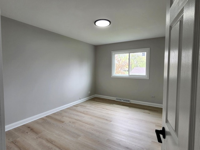 empty room with baseboards, light wood-type flooring, and visible vents