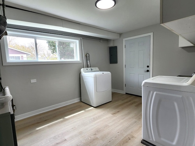 laundry area featuring electric panel, laundry area, light wood-type flooring, baseboards, and washer and clothes dryer