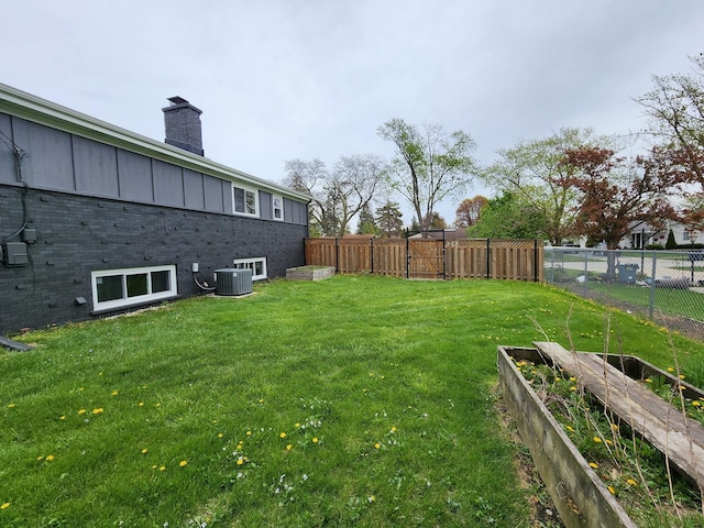 view of yard with fence, cooling unit, and a garden