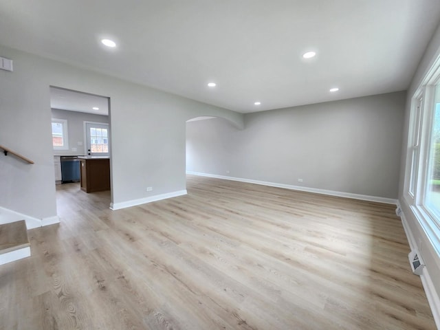 unfurnished living room with a healthy amount of sunlight, arched walkways, and recessed lighting