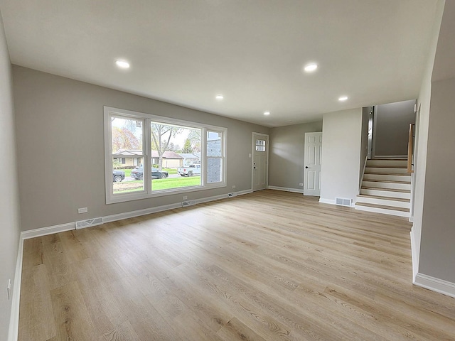 unfurnished living room with visible vents, recessed lighting, baseboards, stairs, and light wood-style flooring