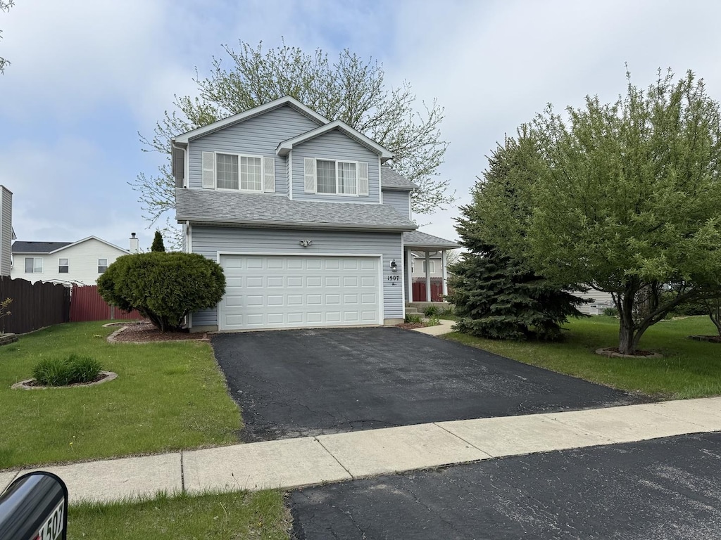 traditional home featuring fence, an attached garage, driveway, and a front yard