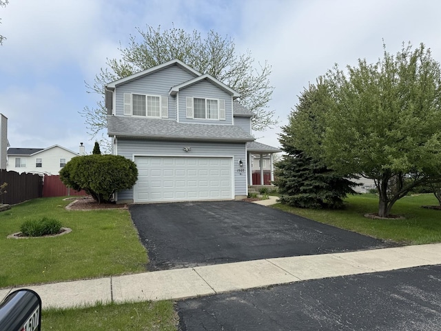 traditional home featuring fence, an attached garage, driveway, and a front yard