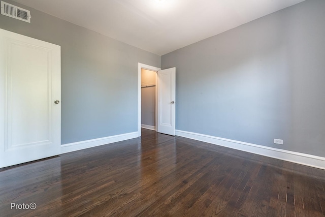 empty room featuring baseboards, visible vents, and dark wood finished floors