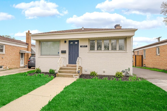 bungalow featuring a chimney, a front lawn, and brick siding