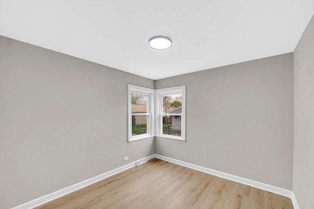 empty room with light wood-type flooring, baseboards, and visible vents