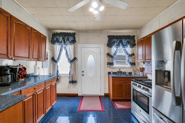 kitchen with a sink, appliances with stainless steel finishes, a ceiling fan, and dark countertops