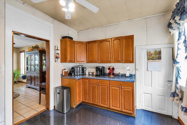 kitchen with dark countertops, brown cabinetry, and a ceiling fan