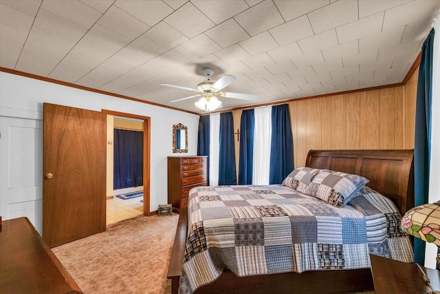 carpeted bedroom featuring crown molding, a ceiling fan, and wood walls