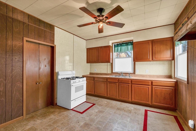 kitchen with a sink, brown cabinets, white gas stove, and light countertops