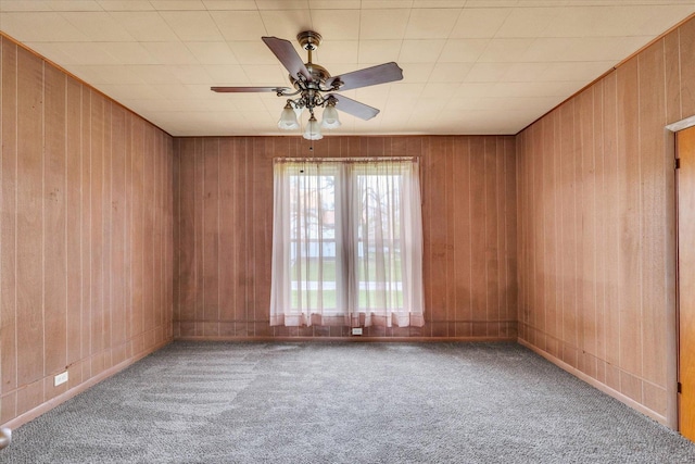 unfurnished room with wooden walls, baseboards, a ceiling fan, and carpet flooring