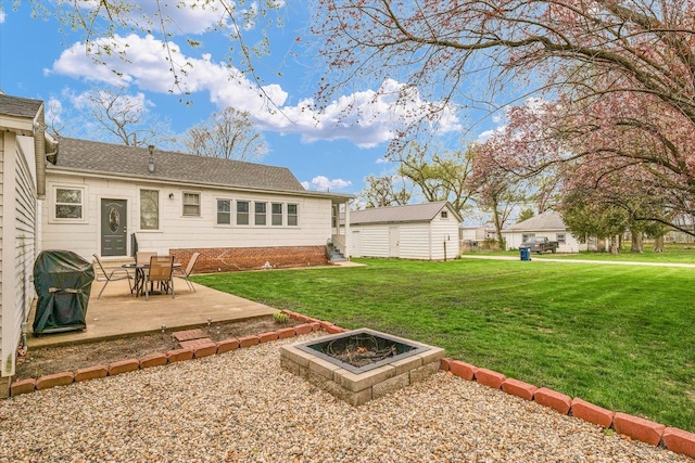 rear view of property featuring a lawn, a shingled roof, an outdoor structure, and a patio area