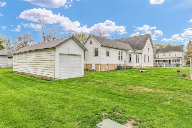 back of property with cooling unit, a yard, an outbuilding, and a detached garage