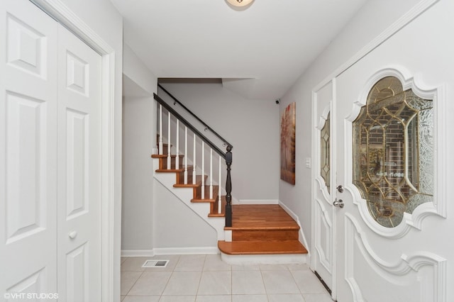 entryway featuring baseboards, light tile patterned floors, and stairway