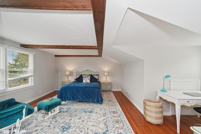 bedroom with baseboards, vaulted ceiling with beams, and wood finished floors