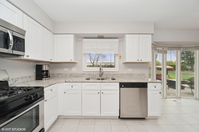 kitchen featuring stainless steel appliances, light tile patterned floors, plenty of natural light, and a sink