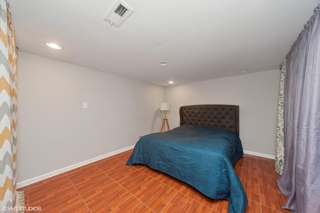 bedroom with baseboards, recessed lighting, wood finished floors, and visible vents