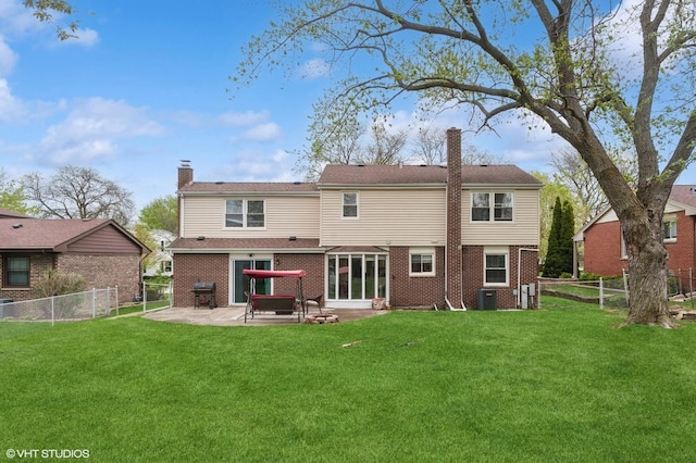 rear view of house with brick siding, a patio, a chimney, and a lawn