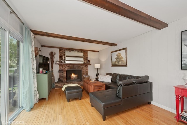 living room featuring light wood-style floors, a fireplace, and beamed ceiling