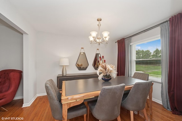 dining room featuring baseboards, wood finished floors, and a notable chandelier
