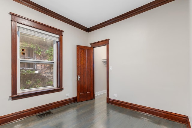 spare room with baseboards, wood finished floors, and crown molding