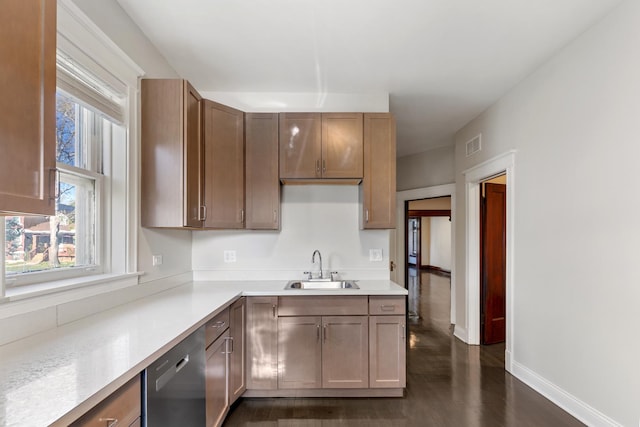 kitchen featuring dishwasher, a sink, light countertops, and dark wood-type flooring