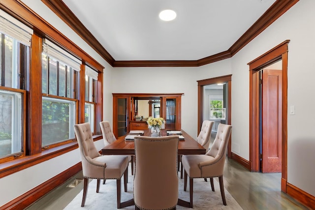 dining space with crown molding, wood finished floors, and baseboards