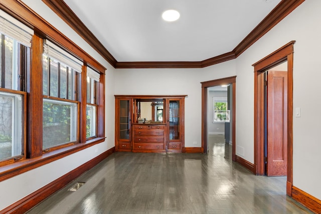 spare room with ornamental molding, baseboards, and dark wood finished floors