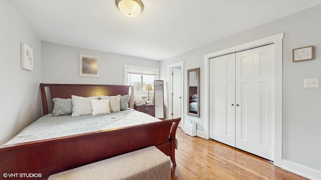 bedroom with light wood finished floors, baseboards, and a closet