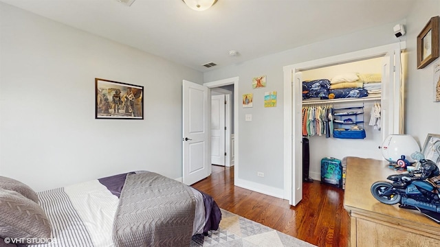 bedroom with wood finished floors, a spacious closet, baseboards, and a closet