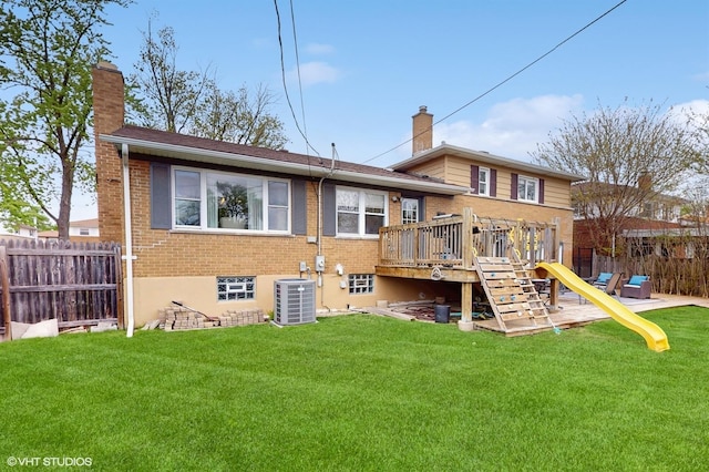 back of house with a chimney, brick siding, central AC, a deck, and a playground