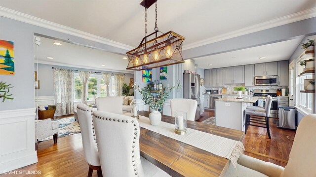 dining area with ornamental molding, wood finished floors, wainscoting, and recessed lighting
