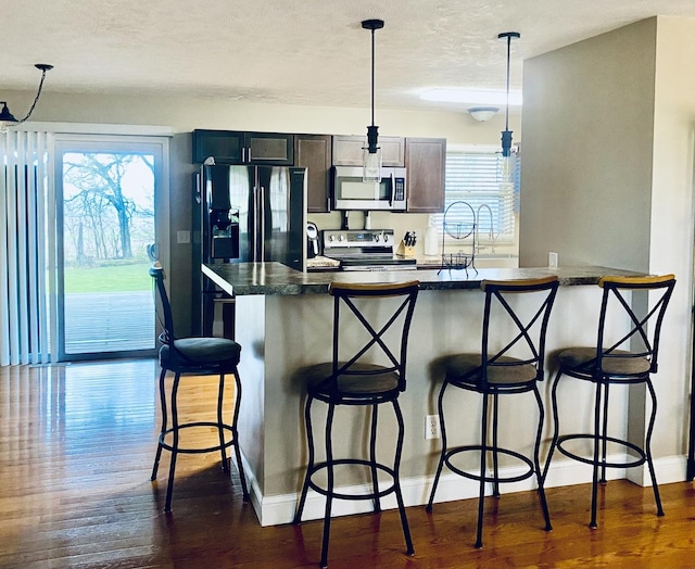 kitchen with dark countertops, plenty of natural light, stainless steel appliances, and dark wood-style flooring