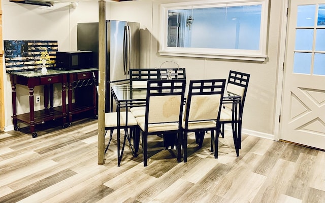 dining space with baseboards and wood finished floors