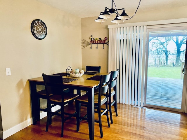 dining area featuring baseboards, an inviting chandelier, and wood finished floors