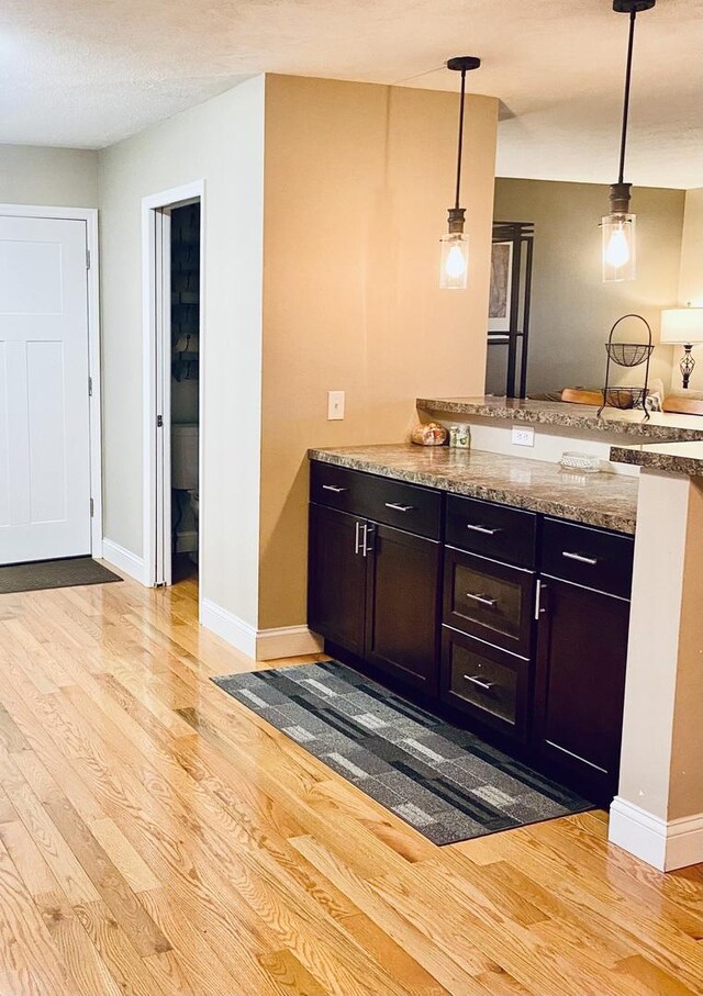 kitchen featuring a peninsula, baseboards, pendant lighting, and light wood finished floors