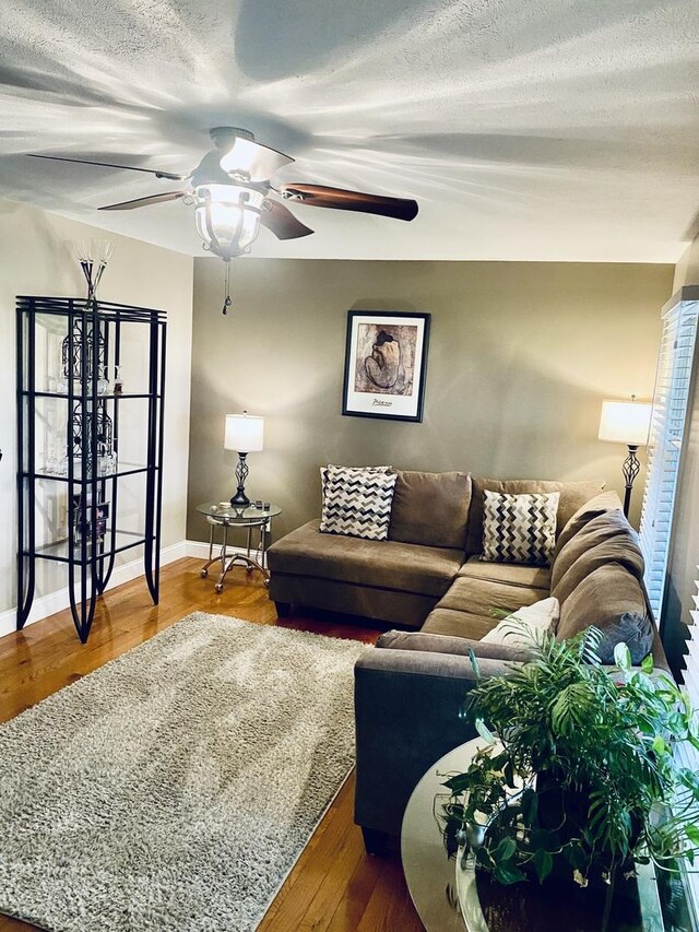 living room with baseboards, a textured ceiling, ceiling fan, and wood finished floors