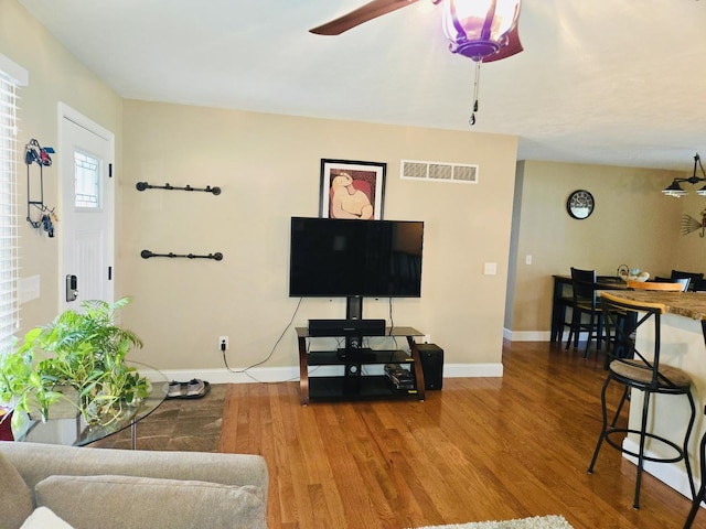 living room featuring visible vents, baseboards, ceiling fan, and wood finished floors