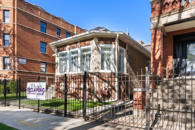 view of front of home featuring a fenced front yard, brick siding, and a gate
