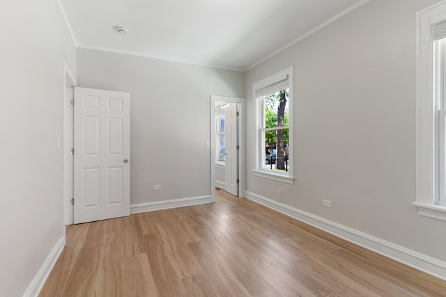 unfurnished bedroom with light wood-type flooring, crown molding, and baseboards