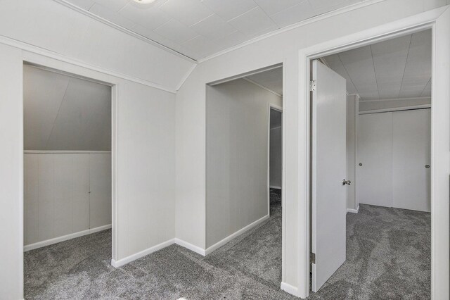 hall featuring crown molding, baseboards, and carpet flooring
