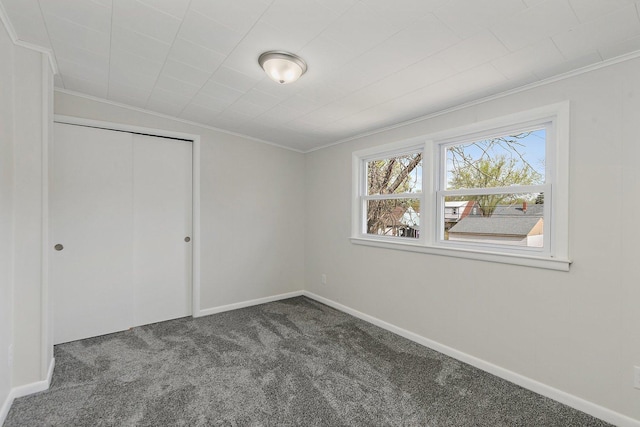unfurnished bedroom with carpet floors, ornamental molding, baseboards, and a closet