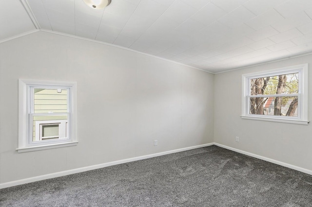 spare room with dark colored carpet, baseboards, and lofted ceiling